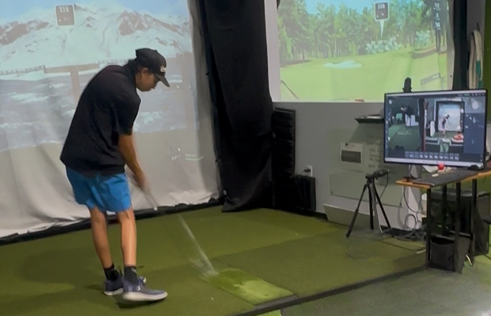 Junior golfer hitting shots in an indoor simulator bay at Golf Performance Group