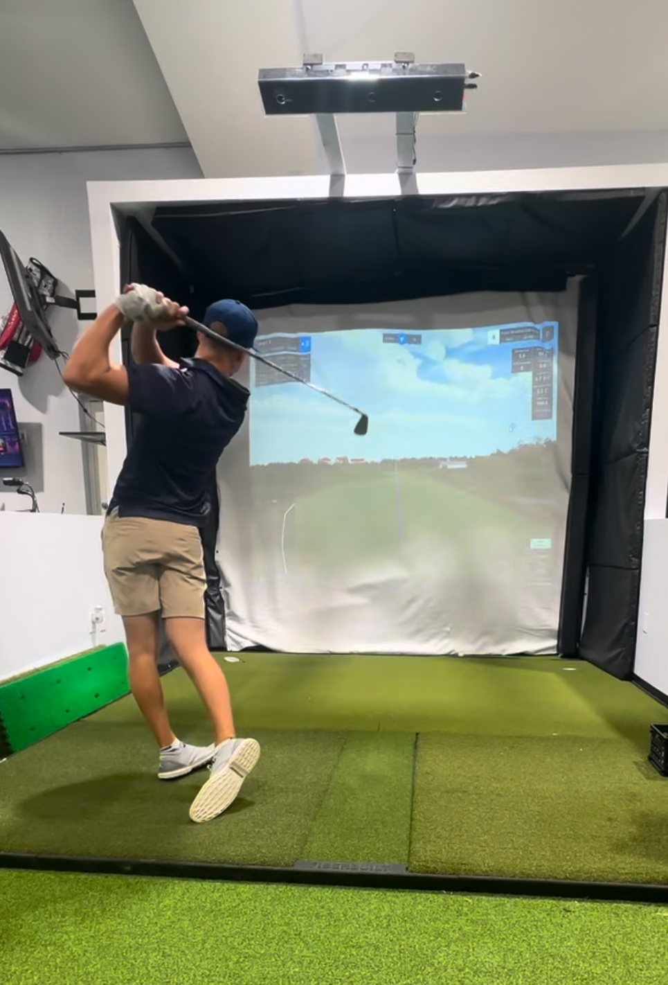 Golfer hitting shots in an indoor bay with launch monitor tracking at Golf Performance Group