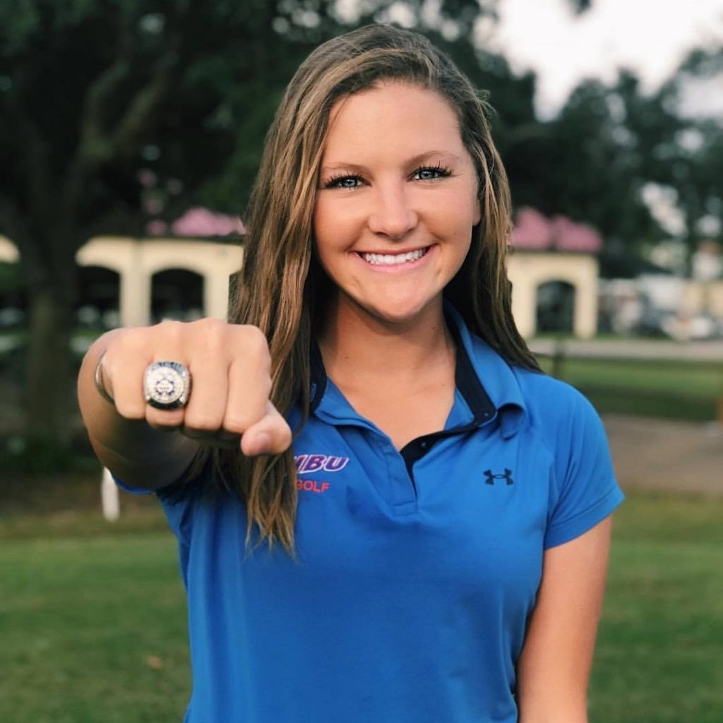 Caylee S. in a college golf team polo showing her championship ring